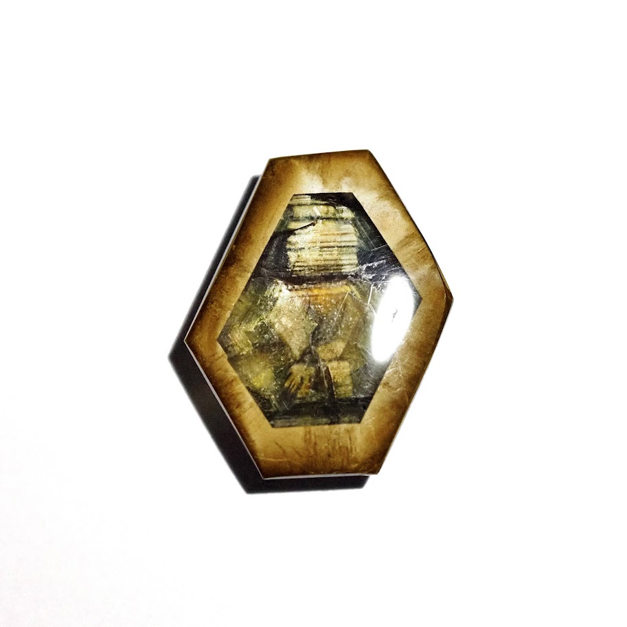 Polished gold sheen sapphire cabochon in a hexagonal cut, warm golden tones